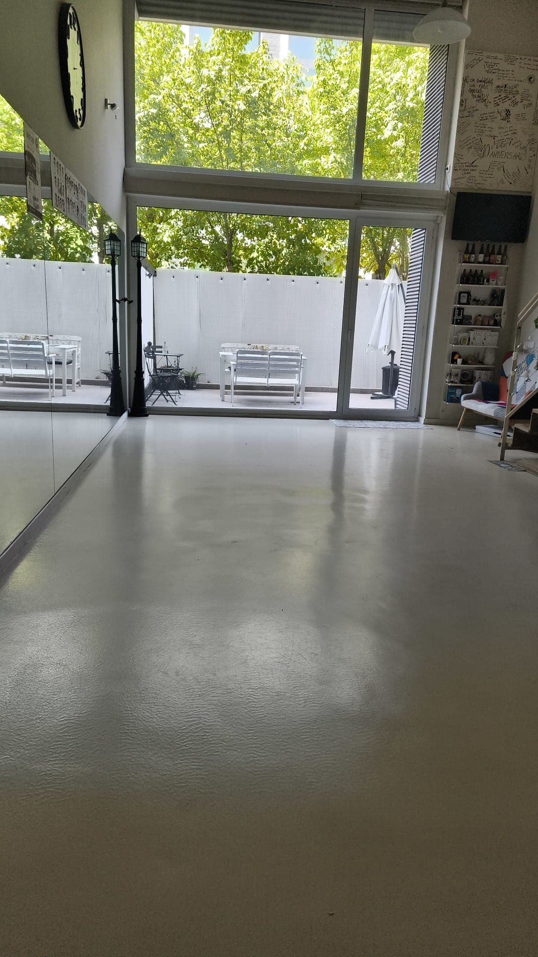 Sala con suelo despejado, espejo lateral y ventanales abiertos hacia la terraza.